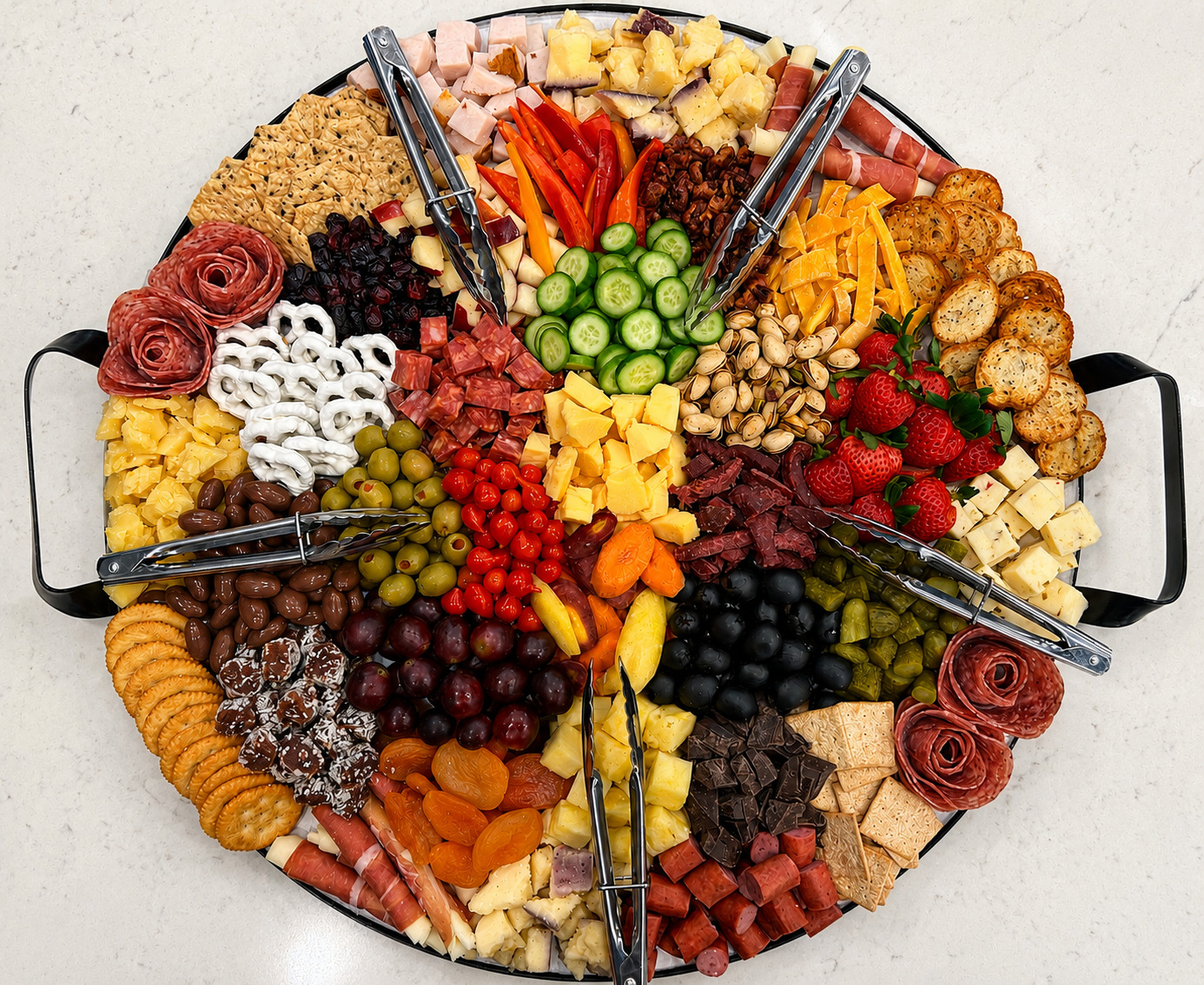 Large round build-your-own charcuterie board loaded with meats, cheeses, fruit and nuts