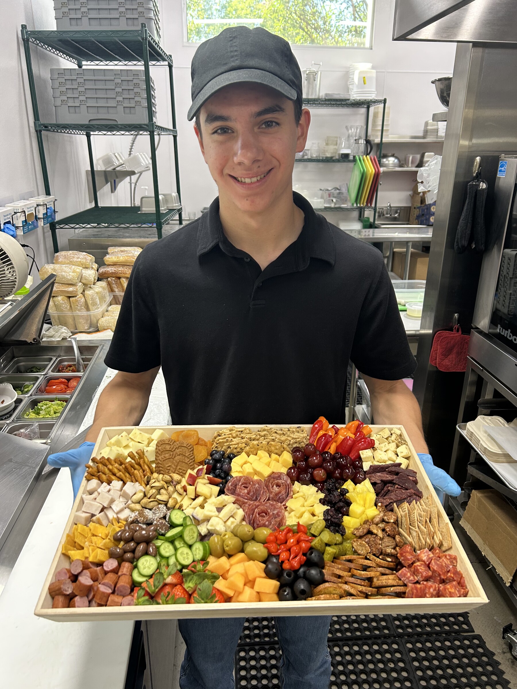 CharQterie team member presenting a large colorful charcuterie board